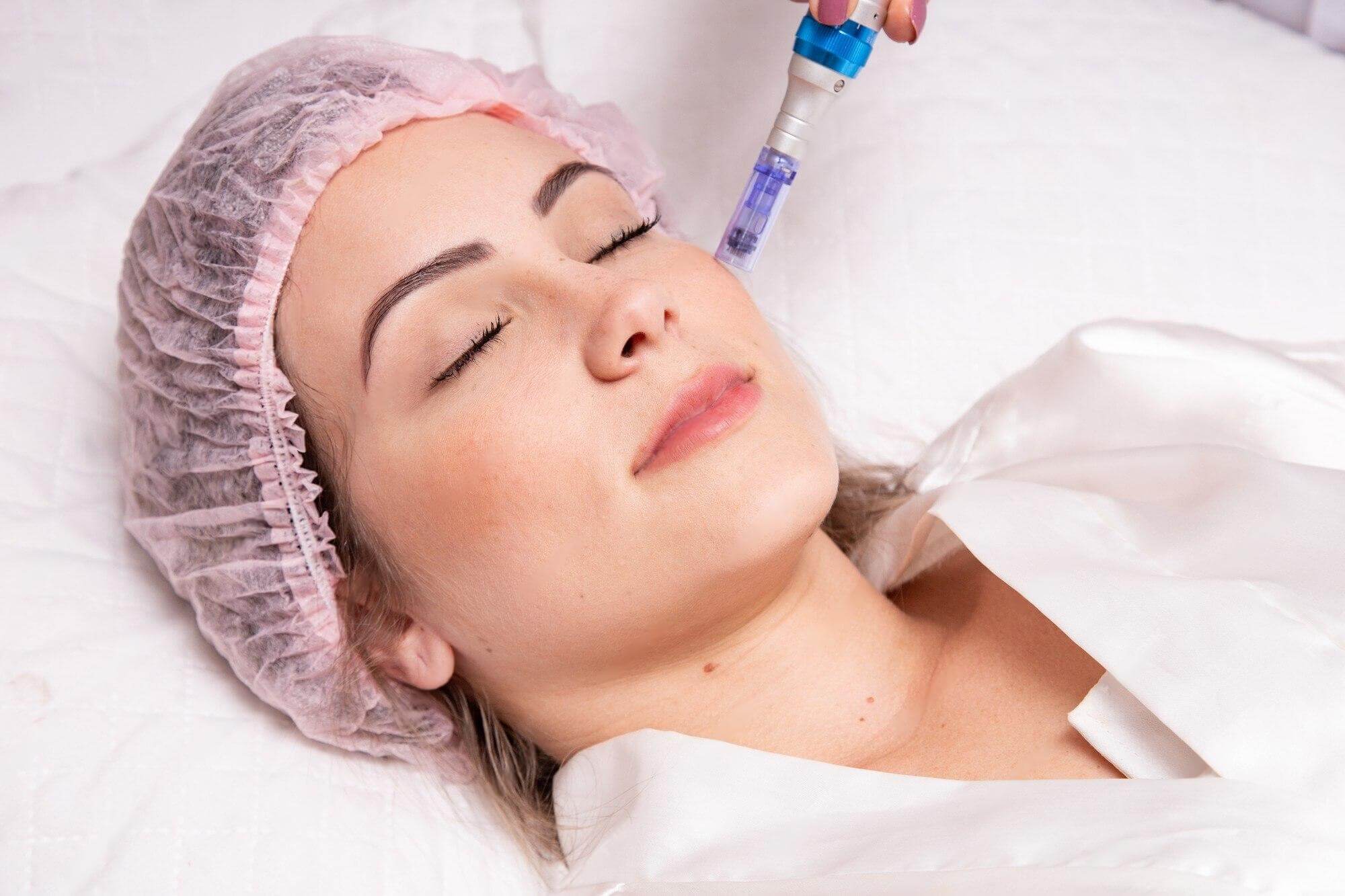 a woman lying down with her eyes closed and a hand holding a needle