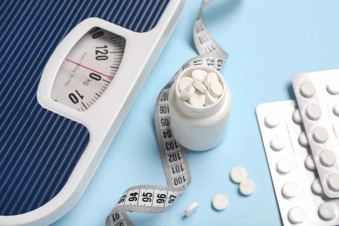 a scale and pills on a blue surface