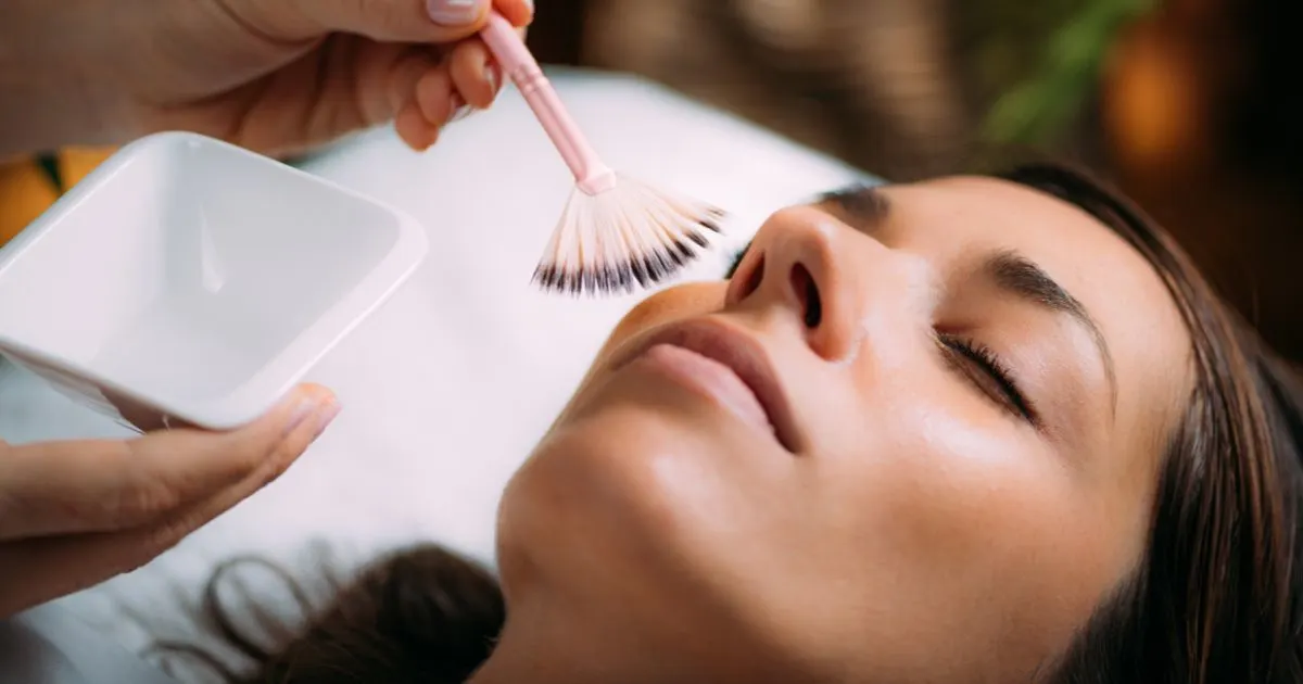 Applying a chemical peel solution with a fan brush to a client's face for skin enhancement treatment at AR Aesthetics.